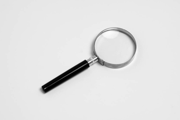 Μαύρη λαβή και μεταλλικό χείλος Μεγεθυντικό γυαλί που απομονώνεται σε λευκό φόντο. Φωτογραφία υψηλής ανάλυσης. - Φωτογραφία, εικόνα