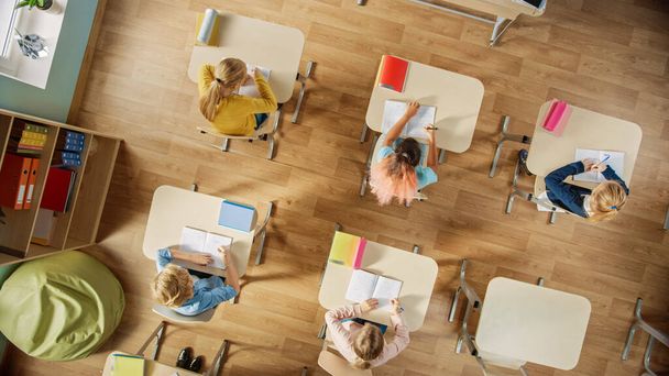 Elementary School Classroom: Children Sitting at their School Desk Working on Assignments in Exercise Notebooks. Top View Shot. - Fotografie, Obrázek