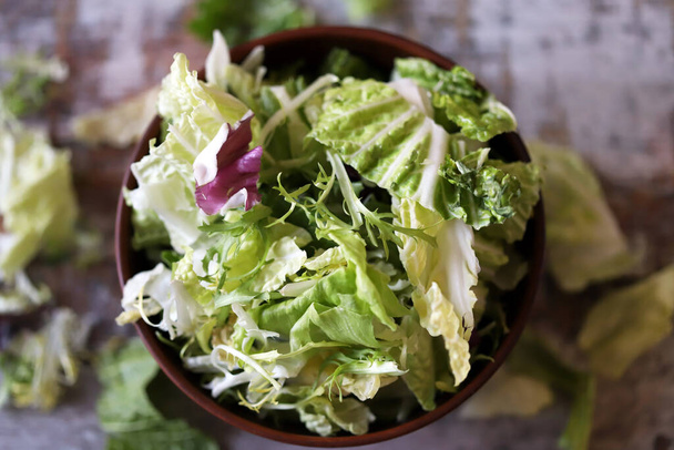 Een mix van salades in een kom. Groene sappige sla bladeren. Het concept van een gezond dieet. Selectieve focus. Blauwe wijting. - Foto, afbeelding