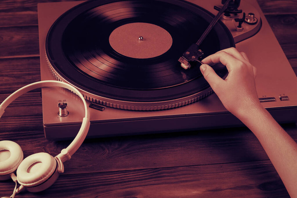 A tinted image of a hand placing a vinyl disc on the player. - Photo, Image