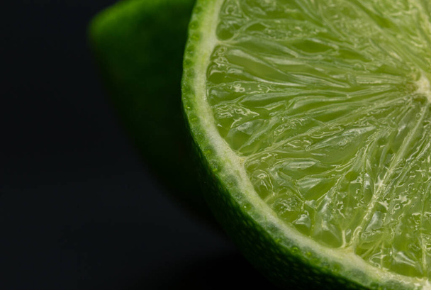 Green lime citruss fruit cutting half macro fiber inside, black background - Photo, Image