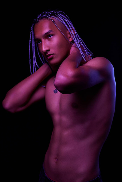 portrait of a young naked african man at studio. High Fashion male model in colorful neon bright lights posing on black background. Art design concept. selective focus. - Foto, Imagem