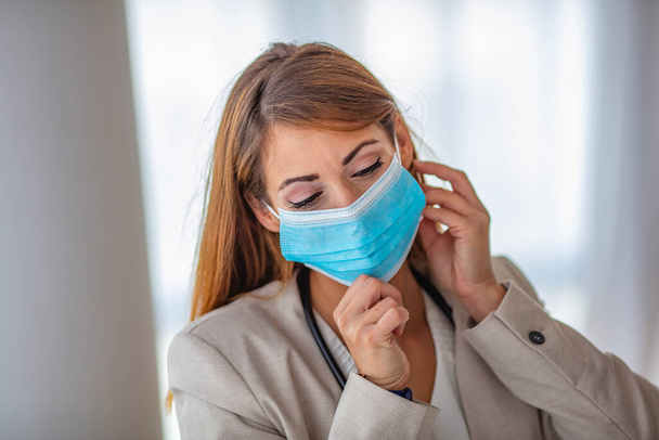 Detail photo of  white woman putting on a blue medical face mask to prevent the flu. Blurred background, focus on the mask. Coronavirus, COVID-19 quarantine. Doctor, nurse concept. - Photo, image