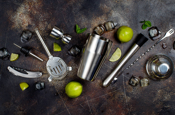 Barkeeper-Werkzeuge, Limette, Minze und Eis auf dunkler Tischplatte - Foto, Bild