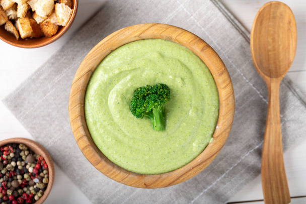 green broccoli cream vegetable soup in a wooden plate on the table. soup decorated with broccoli inflorescenc - Foto, immagini