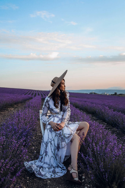 fashion outdoor photo of beautiful sensual woman with dark hair in elegant dress with accessories posing in blooming lavender field - Foto, Imagen