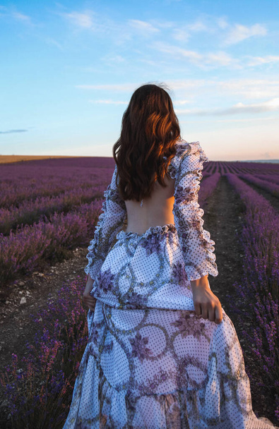 fashion outdoor photo of beautiful sensual woman with dark hair in elegant dress with accessories posing in blooming lavender field - Photo, Image