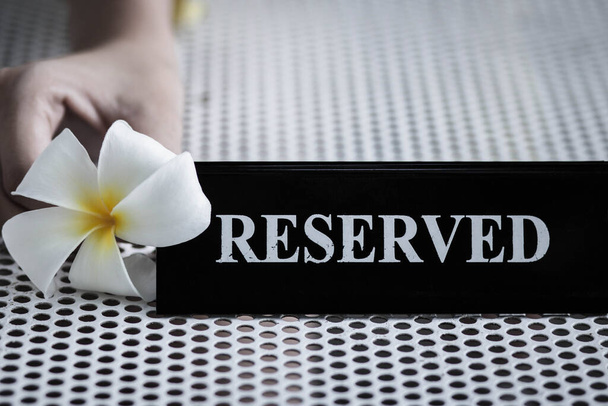 Reserved metal black plate in a restaurant. Reserved metal plate On the white table. vintage photo processing. close up of a setting a reserved sign on the restaurant table. - Photo, Image