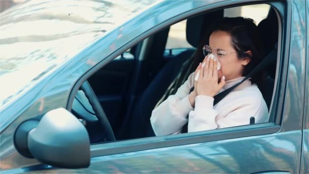 Egy fiatal nő ül az autóban a szünetben. Lassú mozgás a lány szenved a betegség. Női személy a fehér szövetbe fúj. Egyedül a kocsiban.. - Felvétel, videó