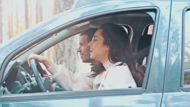 Nuori mies ja nainen ajavat yhdessä autolla metsässä. Iloinen positiivinen naiskuljettaja ja ohjaaja istuvat vierekkäin. Tyttö ratsastaa suoraan kun kaveri puhuu. - Materiaali, video