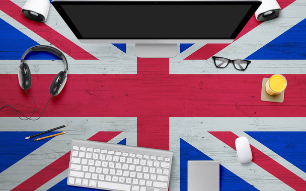 United Kingdom flag background with headphone,computer keyboard and mouse on national office desk table.Top view with copy space.Flat Lay. - Foto, afbeelding