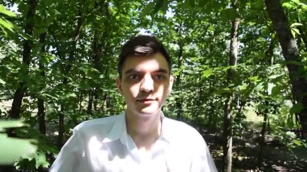 Portrét mladého muže v bílé košili na lesním pozadí - Záběry, video