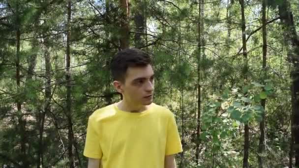 Tişörtlü genç adam ormanda tabancayla ateş ediyor. - Video, Çekim