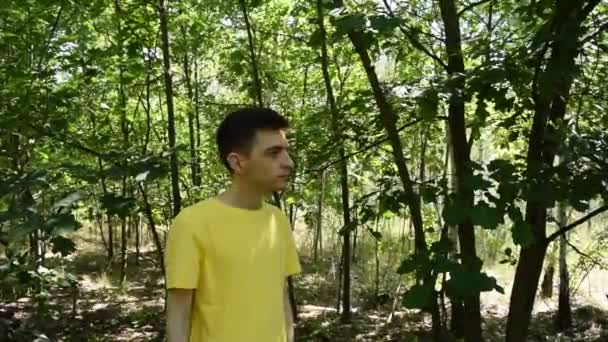 Fiatal srác pólóban lő pisztollyal az erdőben. - Felvétel, videó
