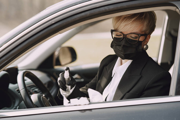Businesswoman in a black mask sitting inside a car - Фото, изображение