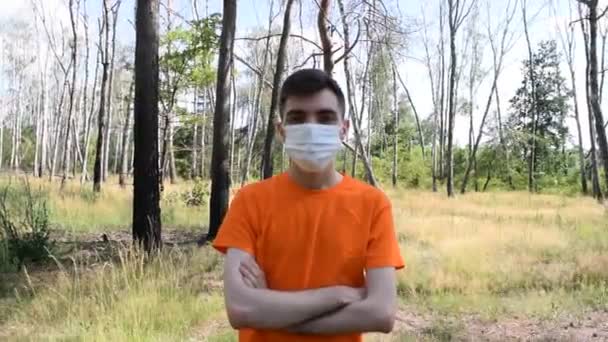 Fiatal férfi pólóban és orvosi maszkban az erdőben. - Felvétel, videó
