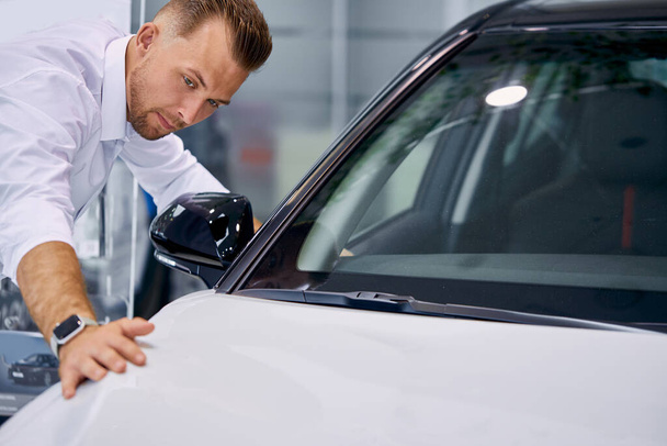 handsome caucasian businessman is examining a car before buying it - Foto, afbeelding