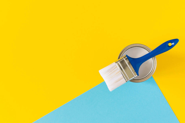 Can of white paint with a blue brush on colorful background, painting, top view - Fotografie, Obrázek