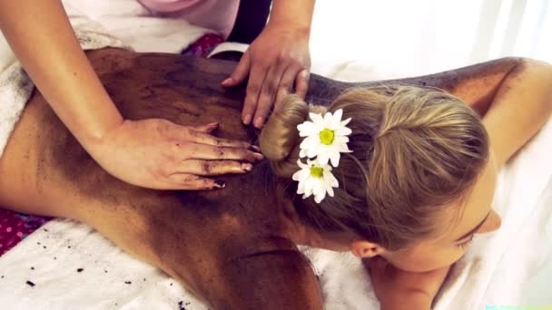Ontspannen vrouw liggend op spa bed voor lichaam schrobben massage met behulp van traditionele kruid - Video