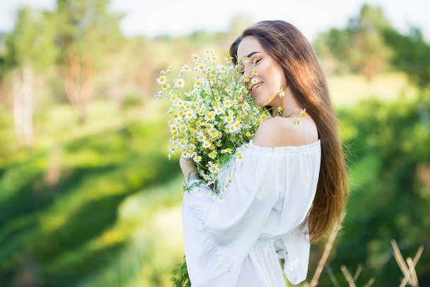 portrait of a beautiful young girl with bouquet, outdoors, in the field - 写真・画像