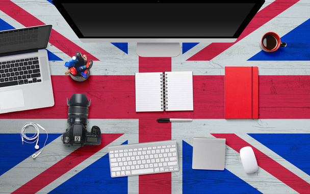 United Kingdom flag background with headphone,camera, notebook and mouse on national office desk table.Top view with copy space.Flat Lay. - Foto, Imagen