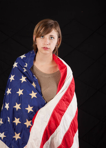 Pretty woman wrapped in an American flag and looking thoughtful - Photo, Image