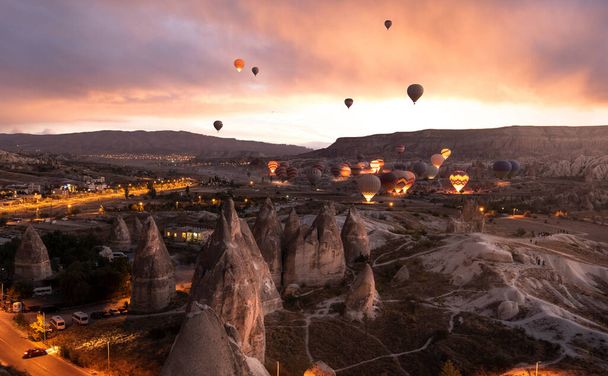 Hermosas escenas en el parque nacional Goreme. Cientos de coloridos globos de aire caliente volando en el cielo al amanecer. Increíbles formaciones rocosas en el valle Capadocia, Turquía - Foto, Imagen