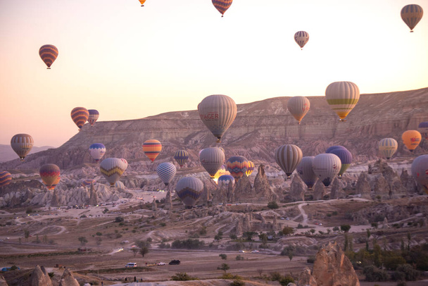 Goreme, Capadocia, Turquía. Hermosas escenas en el parque nacional Goreme. Cientos de coloridos globos de aire caliente volando en el cielo al amanecer. Increíbles formaciones rocosas en el valle - Foto, Imagen