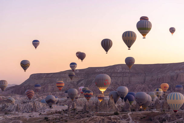 Goreme, Cappadocië, Turkije Prachtige scènes in Nationaal Park Goreme. Honderden kleurrijke hete lucht ballonnen vliegen in de lucht bij zonsopgang. Ongelooflijke rotsformaties in de vallei - Foto, afbeelding