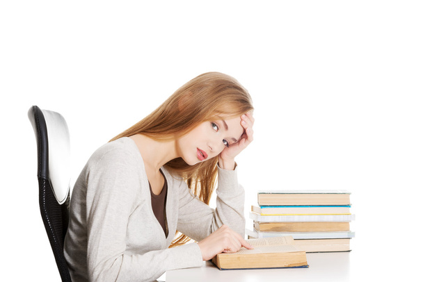 Beautiful casual student woman sitting by stack of books and learning. - Fotoğraf, Görsel