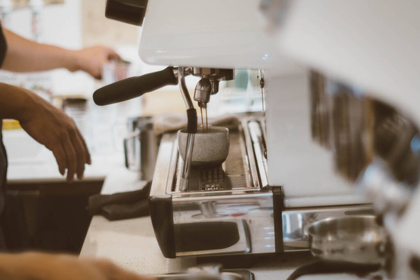 Close-up of barista hand making cup of coffee with coffee maker machine in restaurant or coffee shop. Lifestyles of modern life in city. Business food and drink concept idea - Photo, image