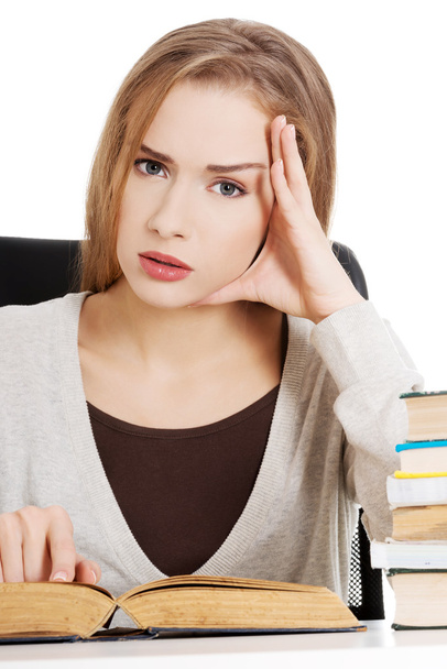 Beautiful casual student woman sitting by stack of books - Photo, image
