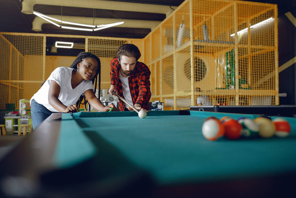 International couple playing a billiard in a club - Фото, зображення