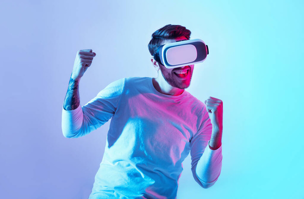 Sanal oyunda kazanmak. VR gözlüklü mutlu adam zafere seviniyor. - Fotoğraf, Görsel