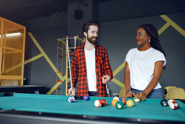 International couple playing a billiard in a club - Photo, image