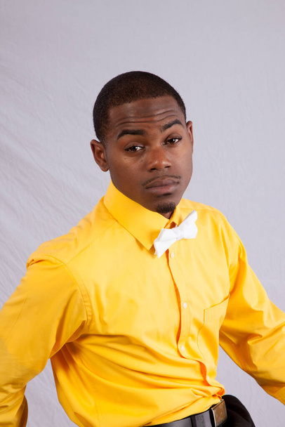 Pensive black man in yellow shirt and white bow tie - Photo, Image