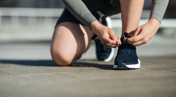 Утренняя пробежка Молодой человек завязывает шнурки на кроссовках, на трассе
 - Фото, изображение