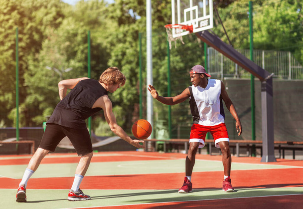 Баскетболисты афроамериканских и кавказских стран играют в футбол на открытом корте
 - Фото, изображение