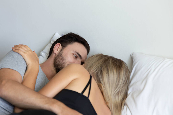 Young cute couple hug and sleep together in bed - Photo, Image