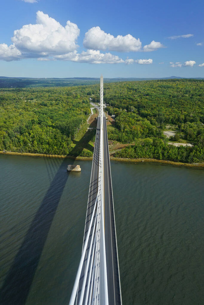 Bucksport, Maine, ABD: Penobscot Narrows Köprüsü üzerinde açık mavi gökyüzünde beyaz bulutlar. Köprü, Penobscot Nehri üzerinde halatla kurulmuş uzun bir köprüdür.. - Fotoğraf, Görsel