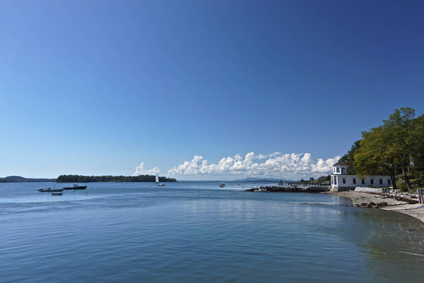 Castine, Maine, USA: Schöne weiße Wolken am blauen Himmel über dem Hafen von Castine, mit kleinen Booten in der Penobscot Bay und Bergen in der Ferne. - Foto, Bild