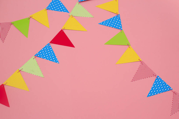 Guirnalda festiva de banderas de papel multicolores sobre un fondo rosa. Tarjeta de felicitación de cumpleaños con espacio para copiar
. - Foto, Imagen