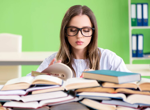 Jonge vrouwelijke student bereidt zich voor op examens met veel boeken - Foto, afbeelding
