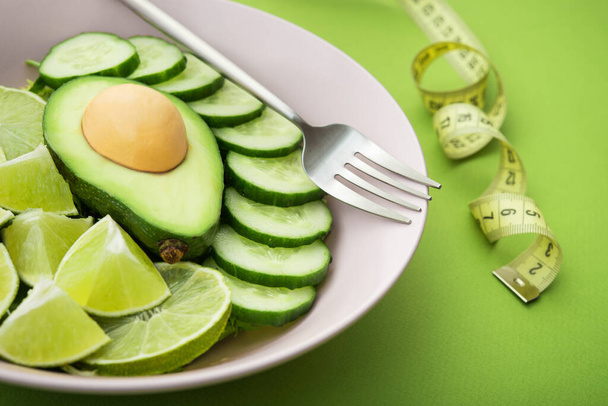 healthy food salad with avocado, lime and cucumber on a green background. Nutrition organic meal - Photo, Image