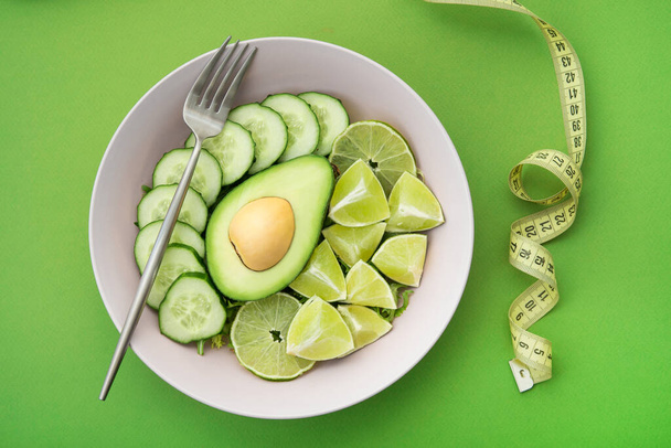 healthy food salad with avocado, lime and cucumber on a green background. Nutrition organic meal - Photo, Image