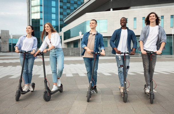 Five friends having pleasant ride on motorized kick scooters - Foto, Imagem