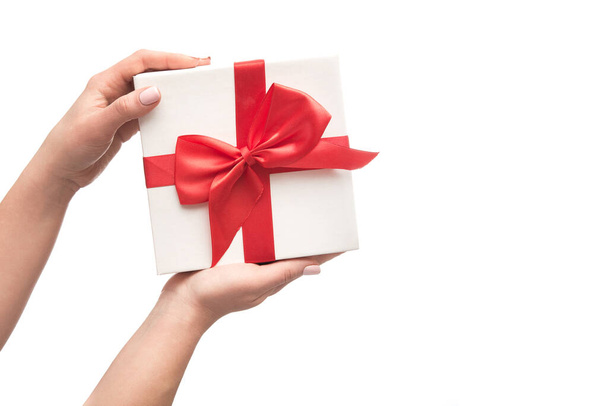 Manos de mujer sostiene caja regalo regalo rojo con cinta aislada sobre un fondo blanco
 - Foto, imagen