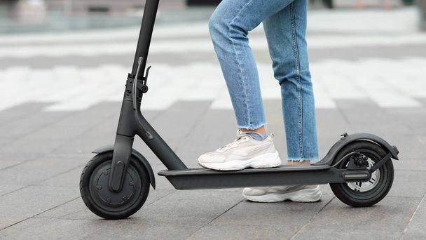 Girl standing on electric kick scooter outdoors - Foto, Bild