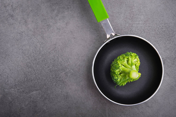 Fresh raw green broccoli in a frying pan. Diet concept background. Top view - Zdjęcie, obraz