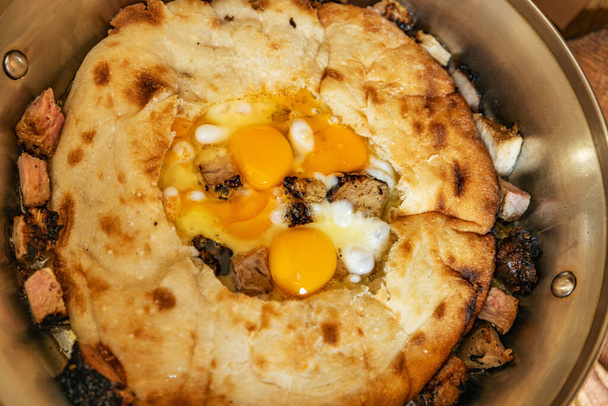 Verse ontbijt gebakken eieren in pitabrood, in een grote koekenpan, close-up, ondiepe velddiepte, selectieve focus. Snel ontbijtconcept - Foto, afbeelding